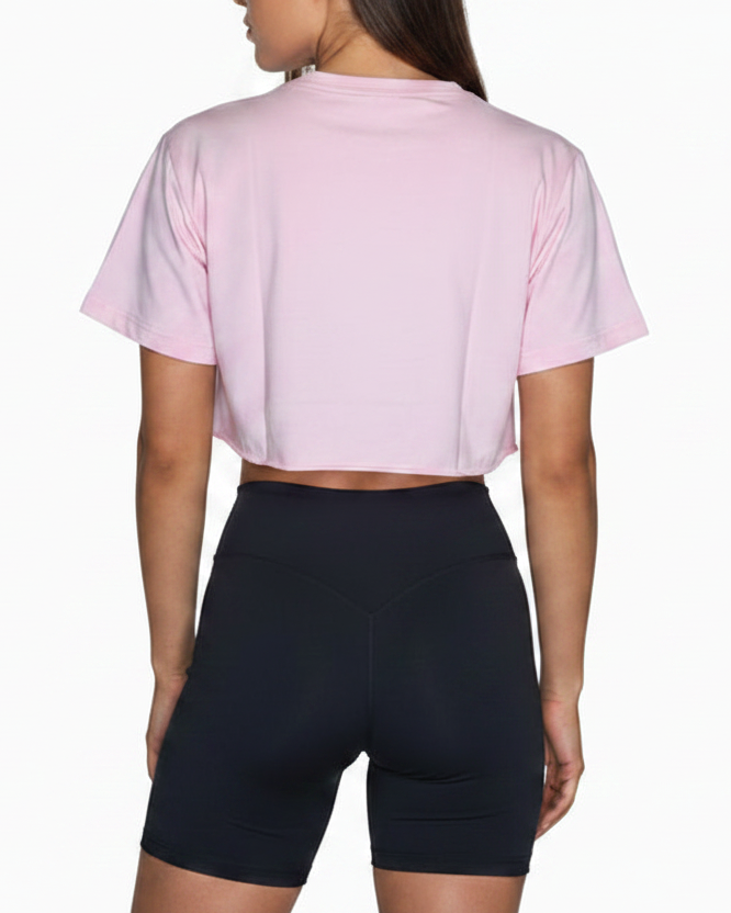Person wearing a pink crop top and black shorts on a white background