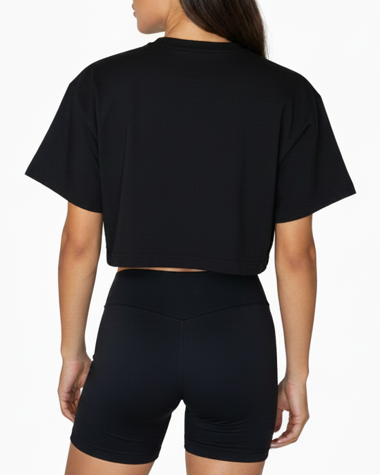 Person wearing a black crop top and black shorts on a white background